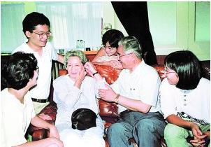 荣毅仁帮助夫人试戴助听器，引得孩子们一阵笑声（资料图片）